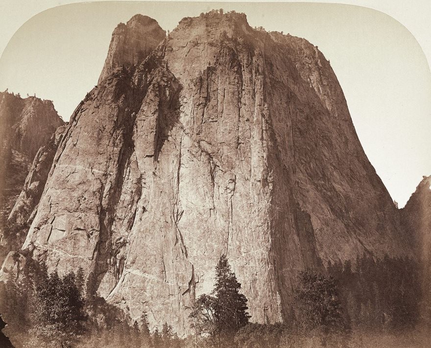 Historic photo of a large rock formation surrounded by trees, capturing the grandeur of nature.