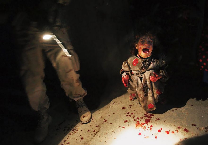 A child crying on a blood-stained floor next to a soldier, depicting a powerful historical photo.