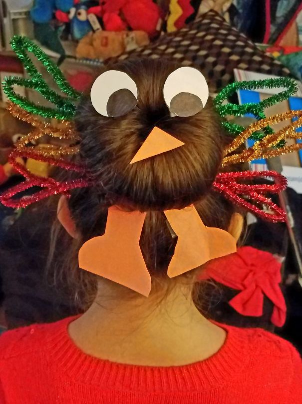 Creative Christmas hairstyle with a bun decorated as a turkey, featuring paper eyes, beak, and colorful pipe cleaner feathers.