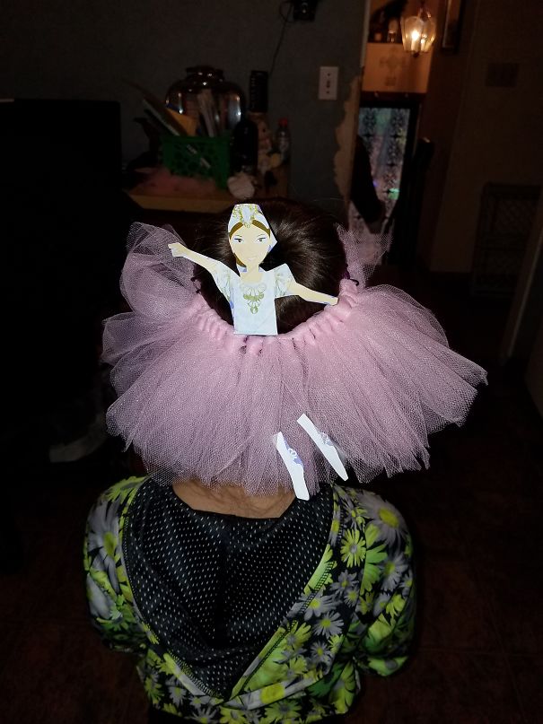 Creative Christmas hairstyle featuring a pink tutu and a paper ballerina ornament on top of a bun.