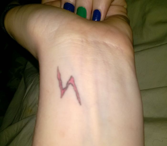 A subtle Harry Potter lightning bolt tattoo on a wrist, with colorful nails visible.