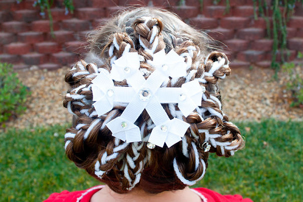Creative Christmas hairstyle featuring intricate braids and decorative white snowflake ornaments.