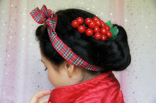 Creative Christmas hairstyle with a plaid headband and red berry accessory, complemented by a festive red jacket.