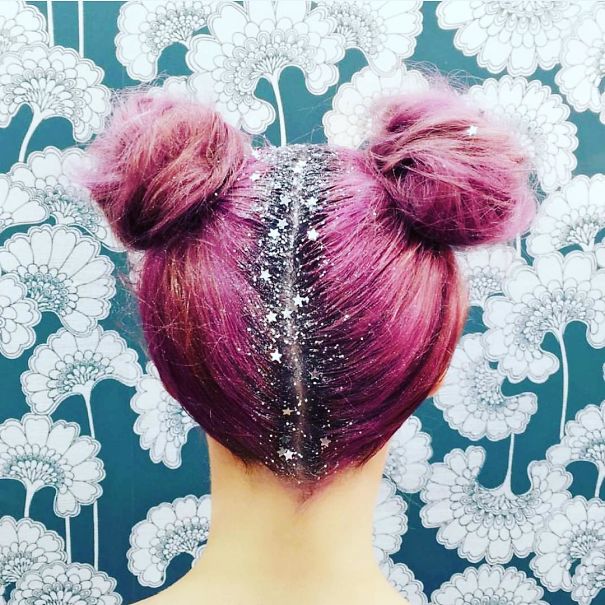 Pink double bun hairstyle with glittery Christmas decoration against floral wallpaper.