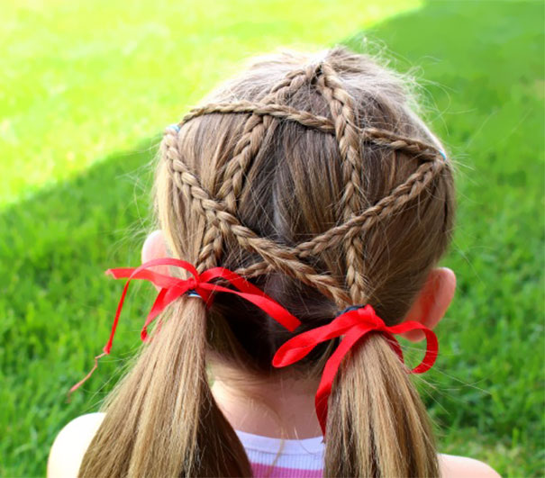 Creative Christmas hairstyle with intricate star-shaped braids and red ribbons.