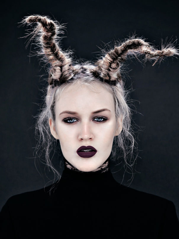 Creative Christmas hairstyle with twisted antler-shaped braids on a person with dark lipstick and dramatic makeup.