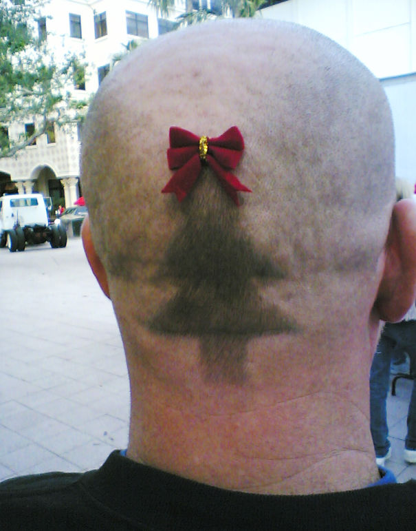 Creative Christmas hairstyle featuring a shaved head with a Christmas tree design and a red bow on top.