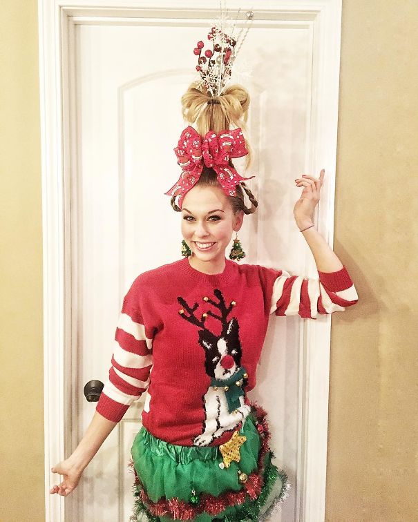 A woman with a tall, creative Christmas hairstyle, featuring a large bow and festive decorations.