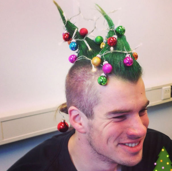 Creative Christmas hairstyle featuring green spiked hair decorated with colorful ornaments and lights.