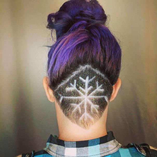 Creative Christmas hairstyle with a snowflake design undercut and purple hair styled in a bun.