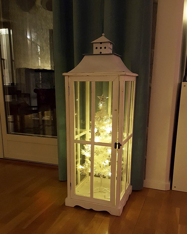 Christmas tree protected in a white glass cabinet to keep it safe from pets.