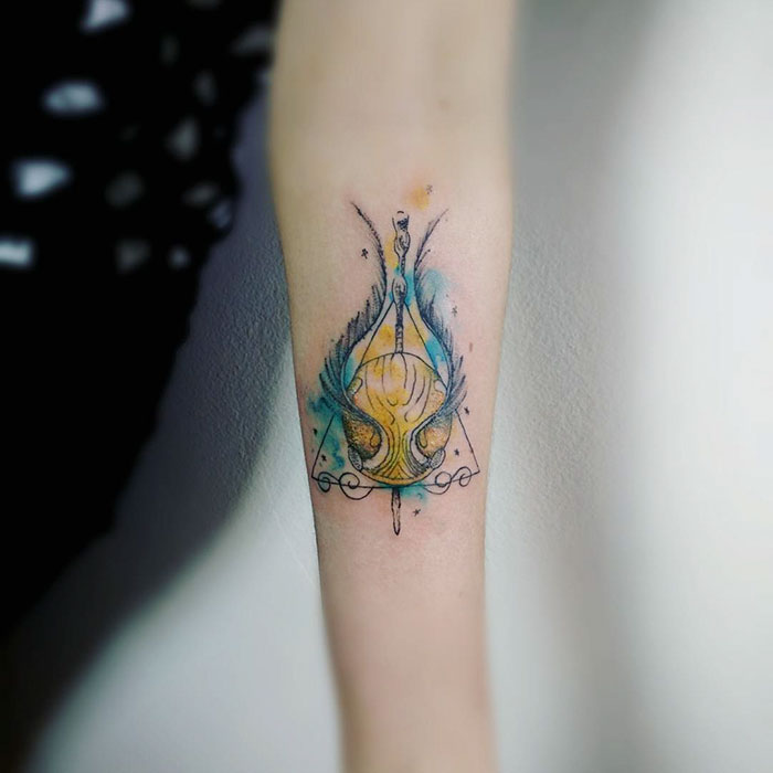 Subtle Harry Potter tattoo with a colorful design on an arm.