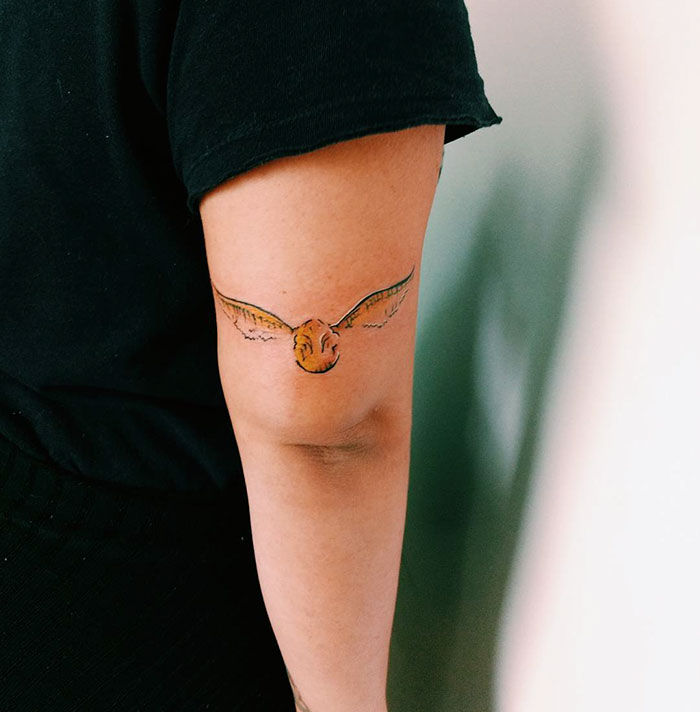 Harry Potter tattoo of the Golden Snitch on an arm, depicting subtle fan art for dedicated Potterheads.