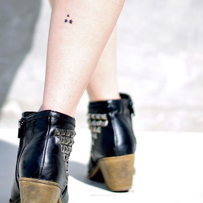 Minimal Harry Potter tattoo of three stars on a person's leg, near ankle boots.