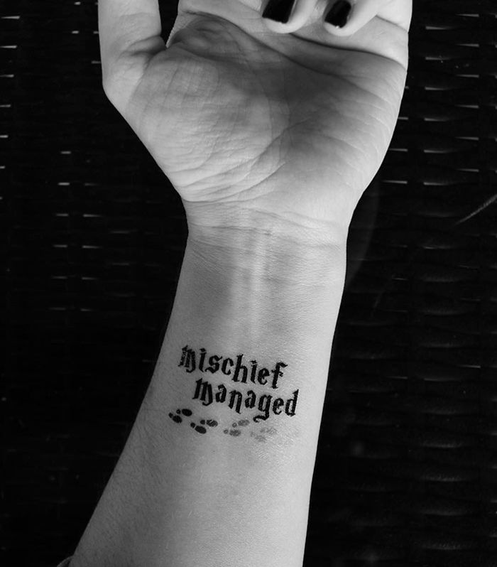 Subtle Harry Potter tattoo on wrist with "Mischief Managed" and footprints design.