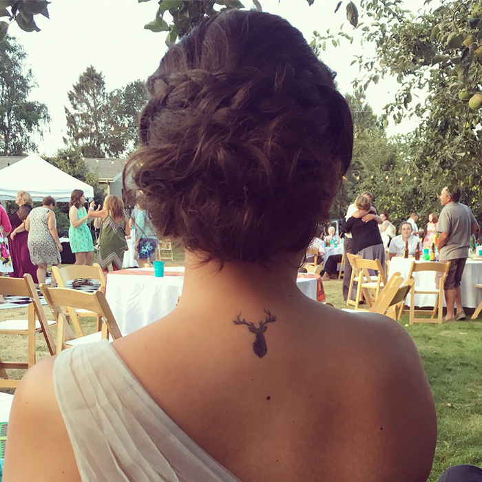 Woman with subtle Harry Potter tattoo of a stag at outdoor event.