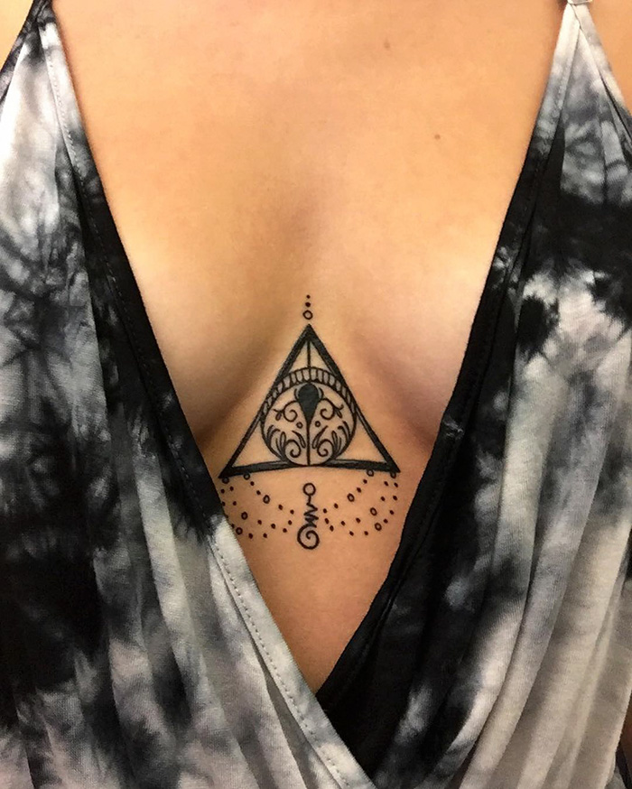 Subtle Harry Potter tattoo featuring the Deathly Hallows symbol with intricate designs on a woman's chest.