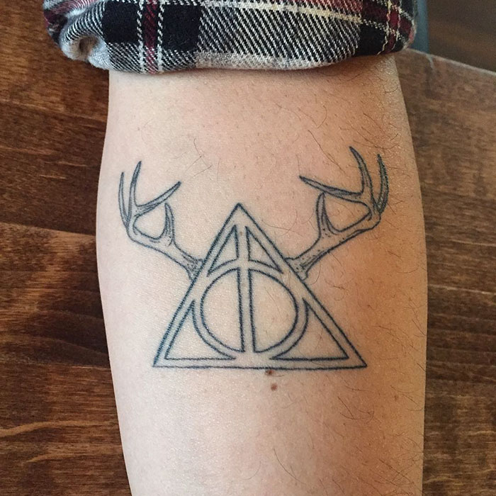 Subtle Harry Potter tattoo of Deathly Hallows with antlers on arm.