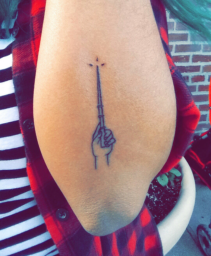 Simple Harry Potter tattoo of a hand holding a wand, symbolizing magic on the forearm.