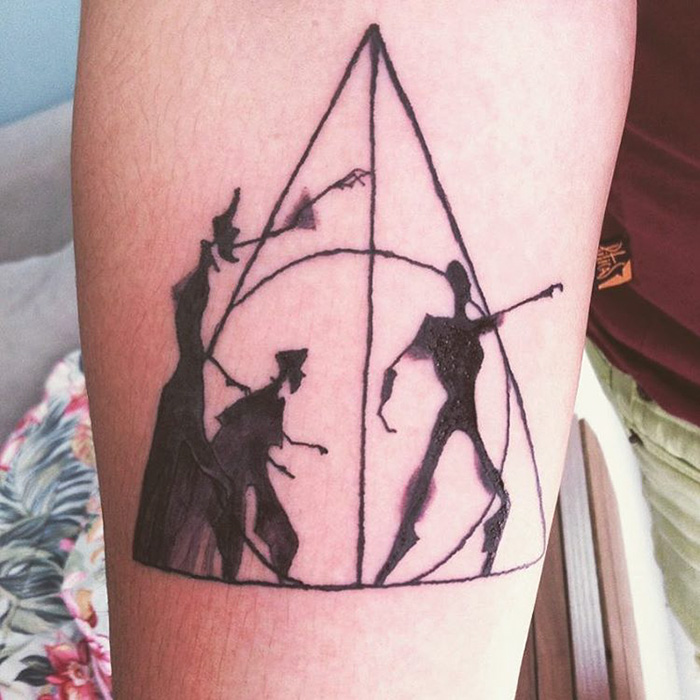 Harry Potter tattoo featuring the Deathly Hallows symbol with subtle character silhouettes.