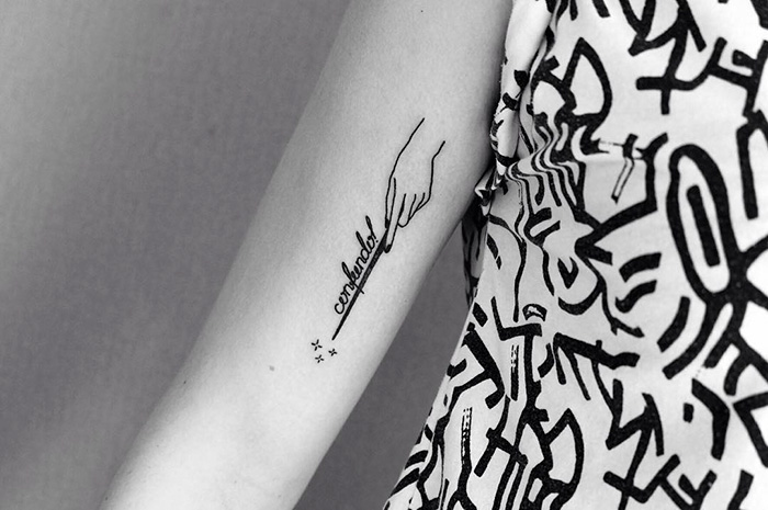 Subtle Harry Potter tattoo of a hand with the word "confundo" on an arm.