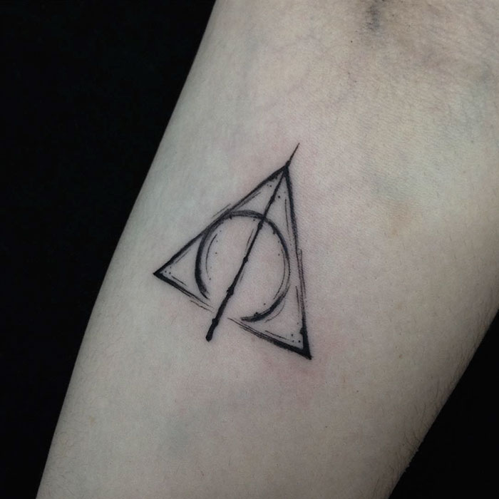 Harry Potter tattoo featuring the Deathly Hallows symbol on skin.