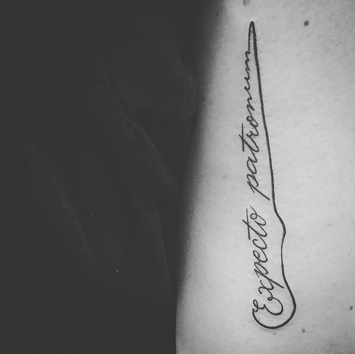 Subtle Harry Potter tattoo of "Expecto Patronum" in elegant script on arm.