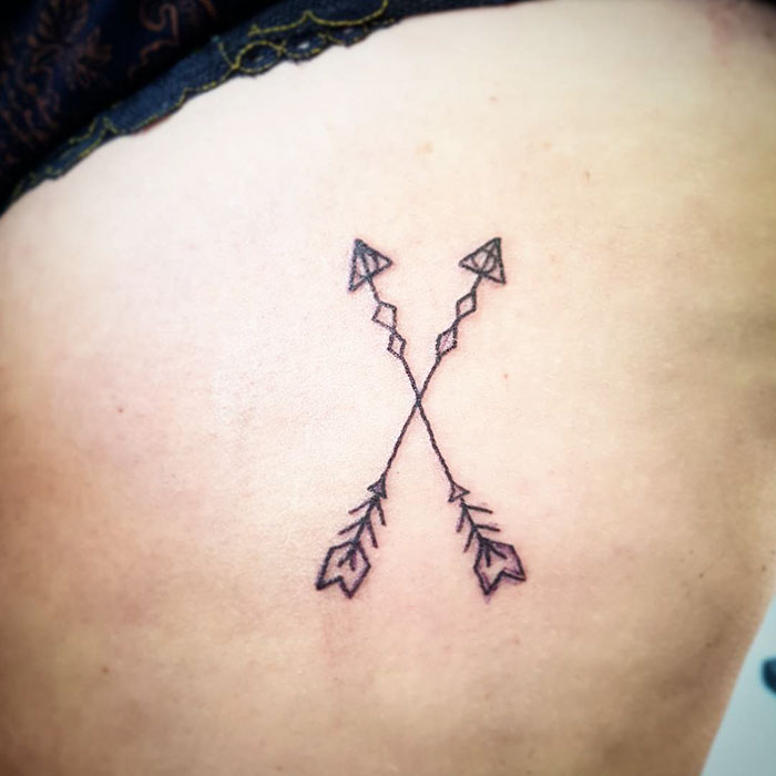 Two minimalist arrows crossed in a subtle Harry Potter tattoo design.