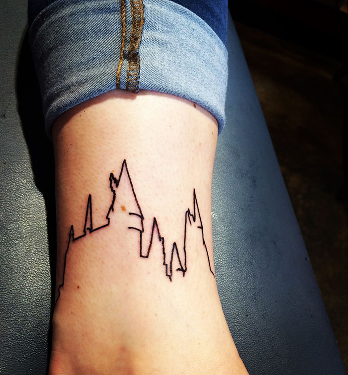 Minimal Harry Potter tattoo of Hogwarts castle outline on ankle.