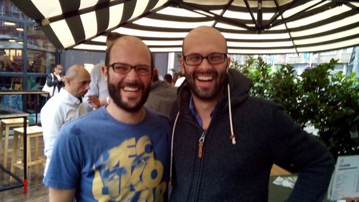 Two doppelgangers laughing under an umbrella 