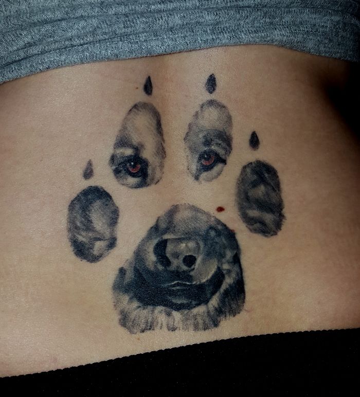 Dog tattoo featuring a paw print with a realistic dog face design.