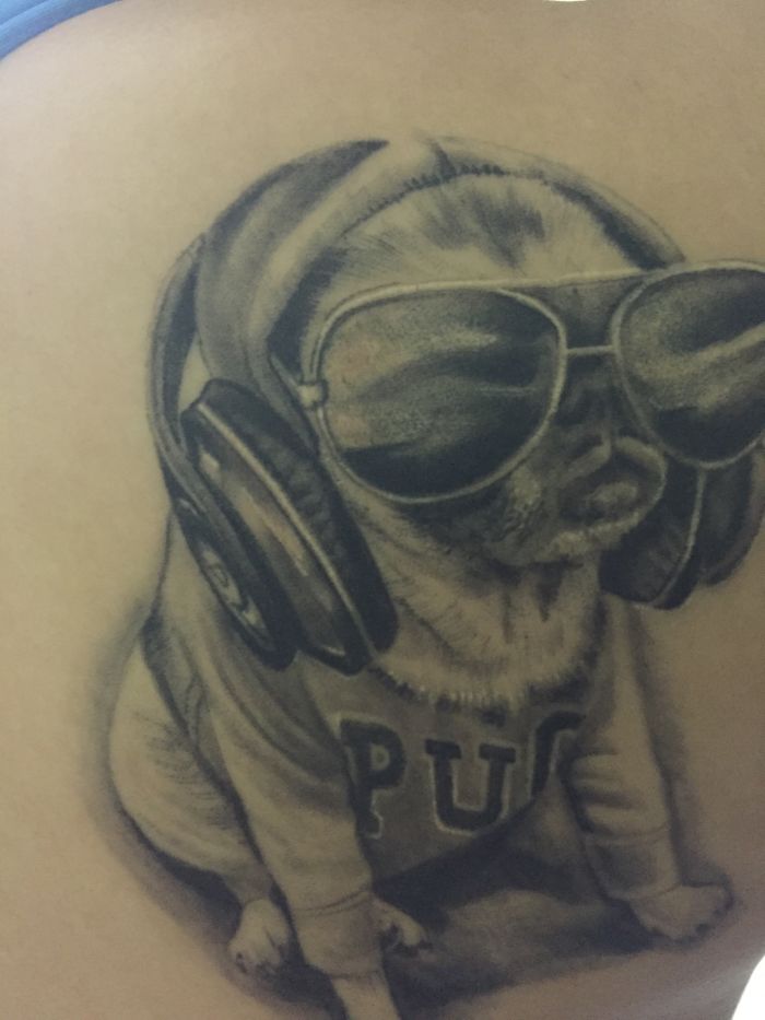 Dog tattoo featuring a pug in headphones and sunglasses, creating a cool and stylish look.