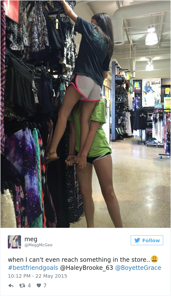 Two girls help each other reach a high shelf in a clothing store, illustrating short people problems.