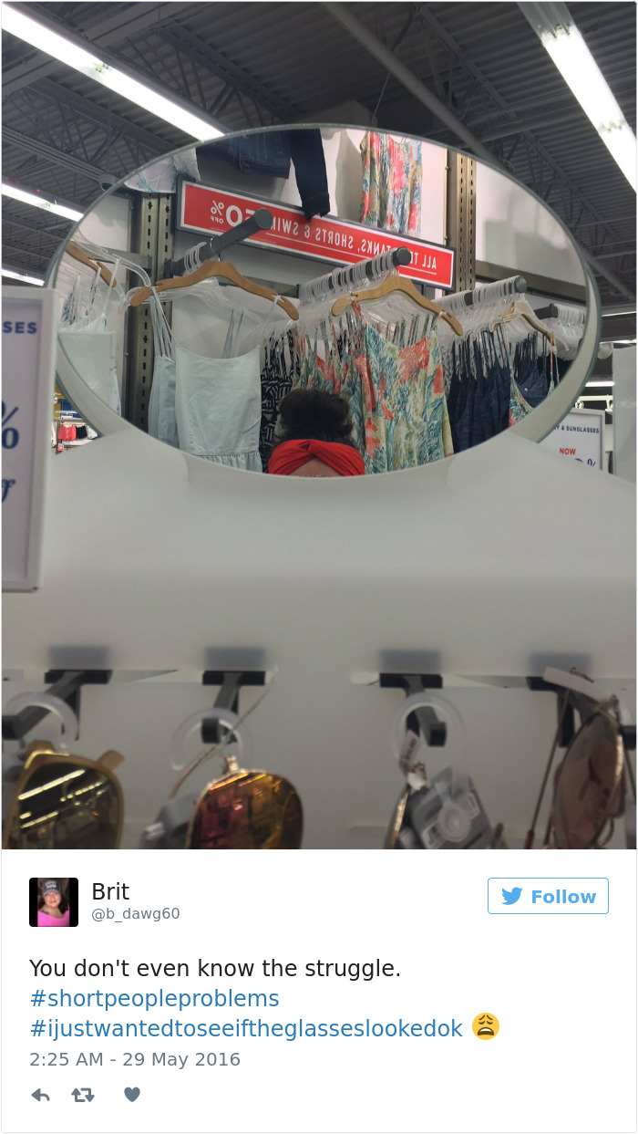 Store mirror selfie humorously captures short people problems with clothes hanging out of reach above.