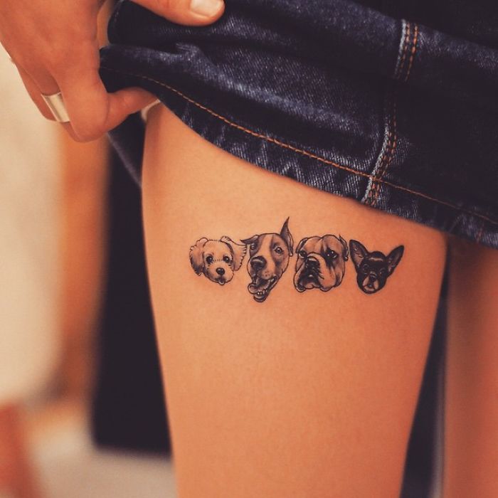 Four dog faces tattooed on a person's thigh, showcasing unique dog tattoo ideas.