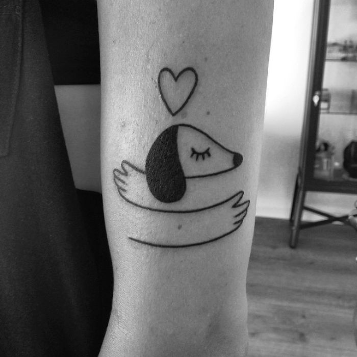 Minimalist dog tattoo design with a heart on arm.