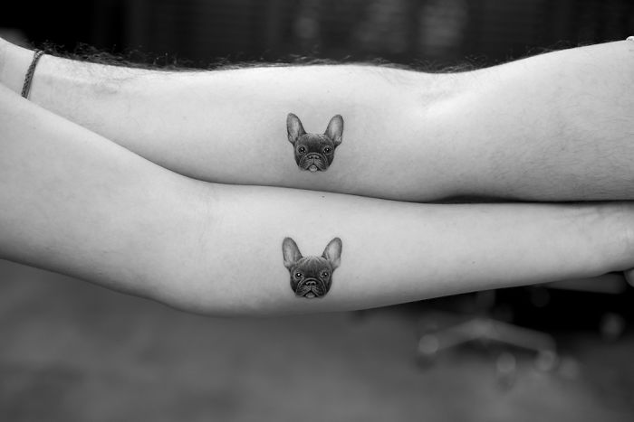 Two forearms featuring identical dog tattoos of a French Bulldog face.
