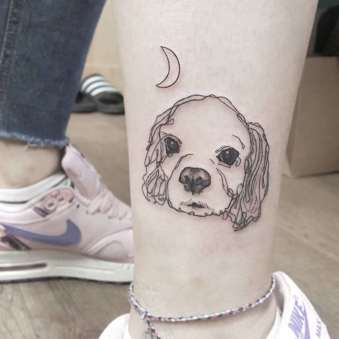 Simple dog tattoo with a moon above, located on a person's leg.
