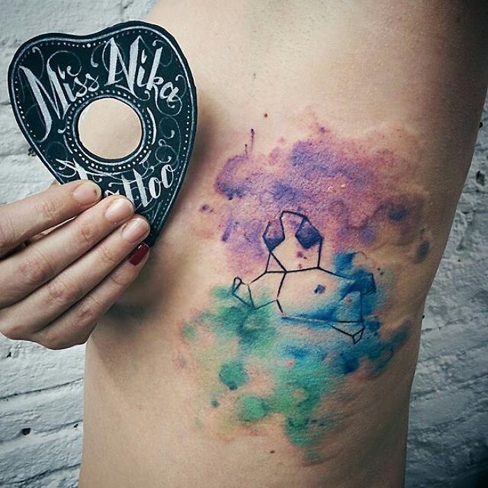 Abstract dog design tattoo with geometric and watercolor elements on skin.