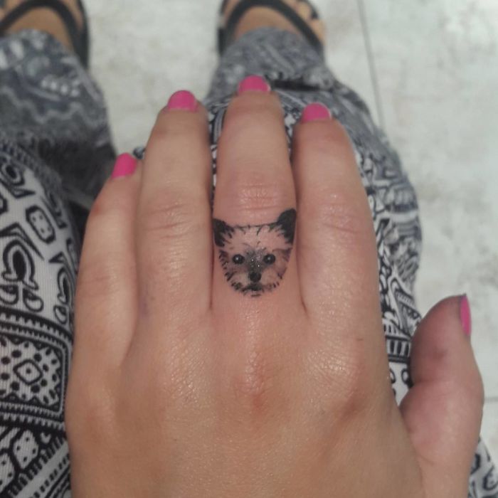 Small dog tattoo on a finger, showcasing intricate design and craftsmanship.