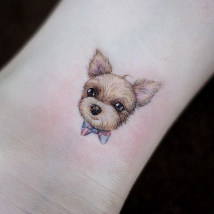 Cute dog tattoo idea featuring a small dog face with a bowtie on the wrist.