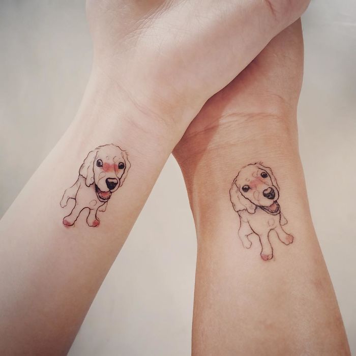 Matching dog tattoos on wrists, featuring cute puppy designs.