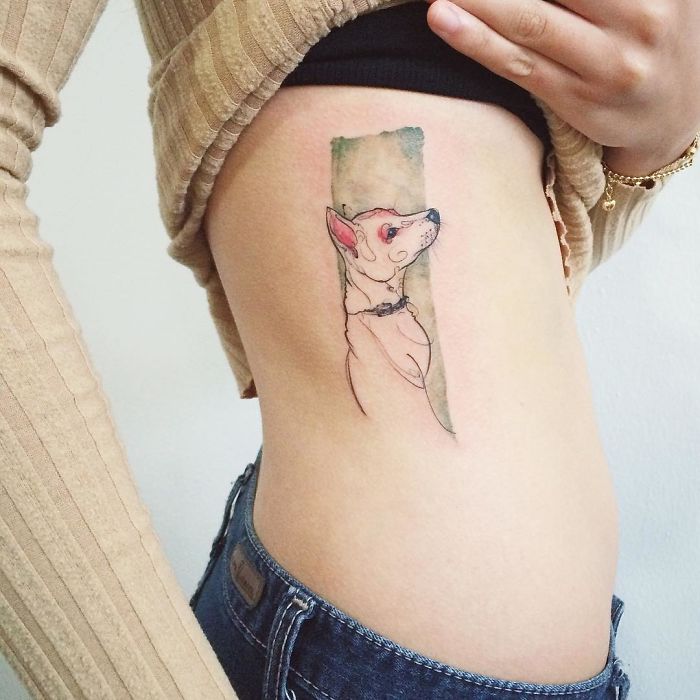Minimalist dog tattoo on a person's side, featuring a Chihuahua with watercolor background.