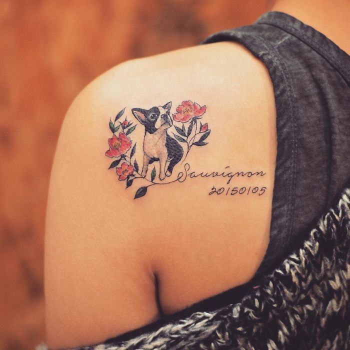Dog tattoo on shoulder with floral design, featuring a small black and white dog.