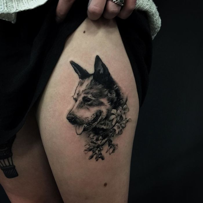 Dog tattoo on thigh featuring a detailed canine portrait with floral accents.