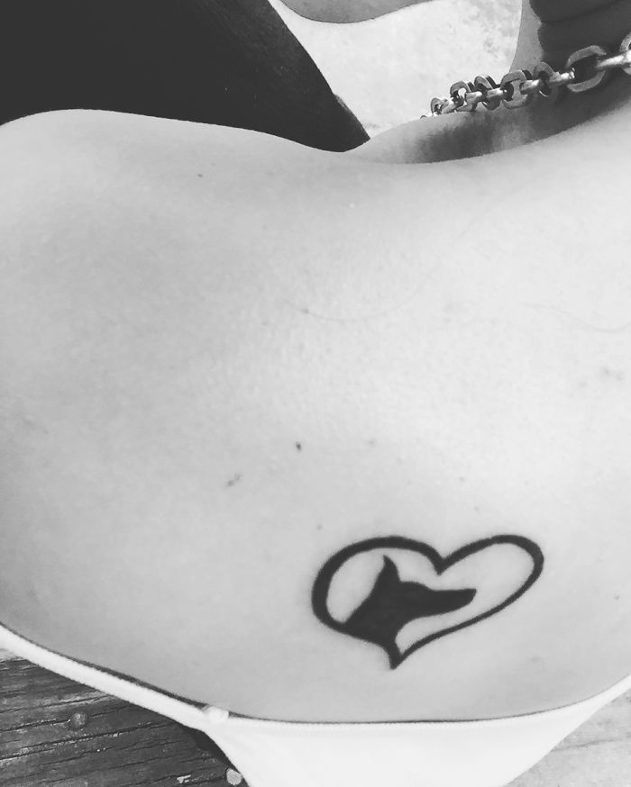 Black and white heart-shaped dog tattoo on shoulder, showcasing creative dog tattoo art.