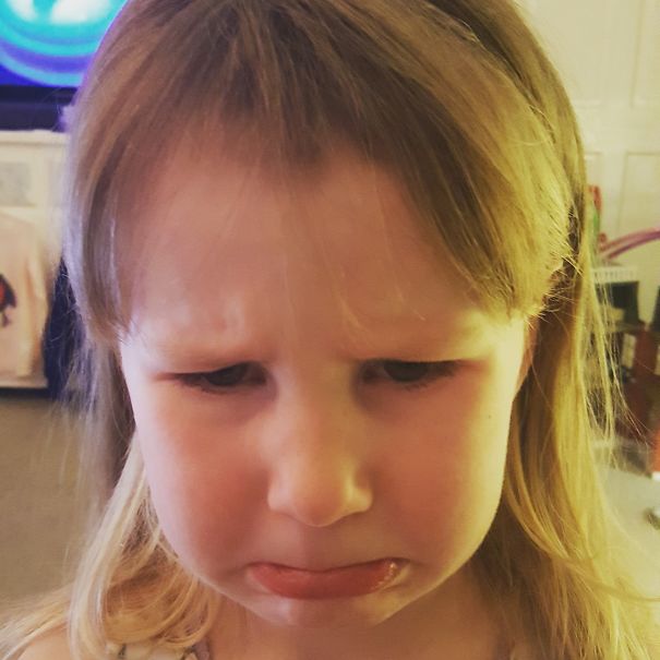 A child with a sad expression after cutting their own hair.