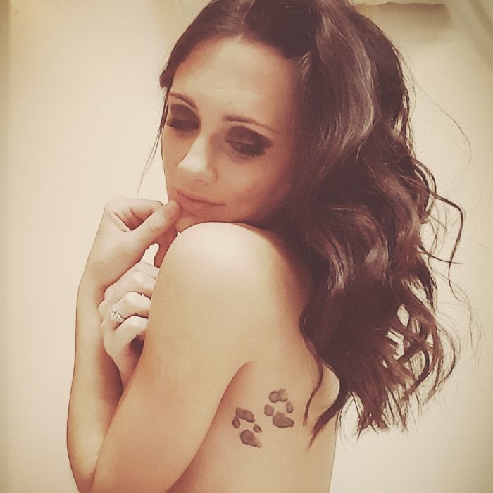 Woman with a dog tattoo of paw prints on her shoulder, showing one of the best dog tattoo ideas.