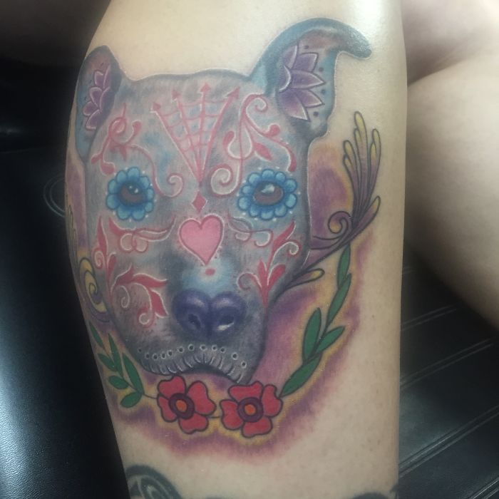 Colorful sugar skull dog tattoo with floral accents and vibrant patterns.