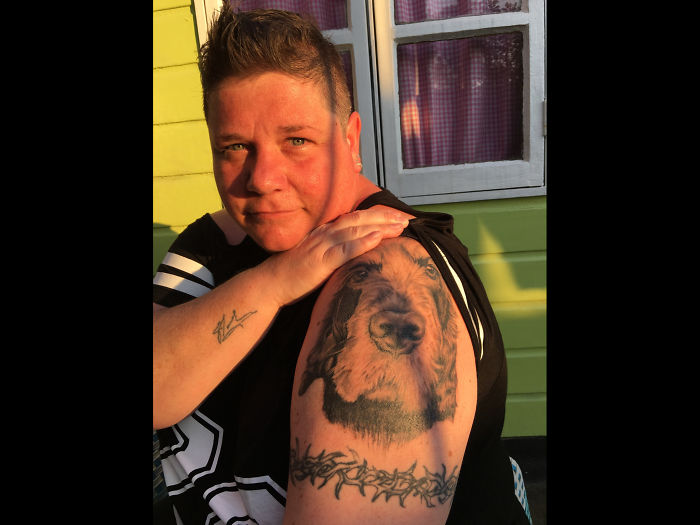 Person showing a detailed dog tattoo on their upper arm.